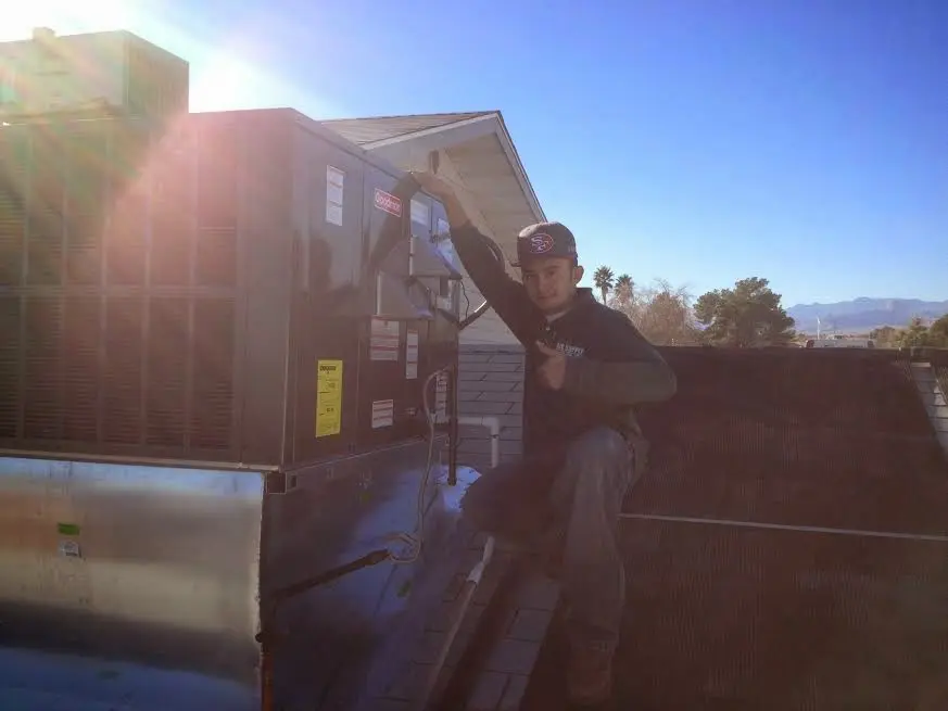 HVAC technician performing Boiler Repair on a rooftop unit in Celina