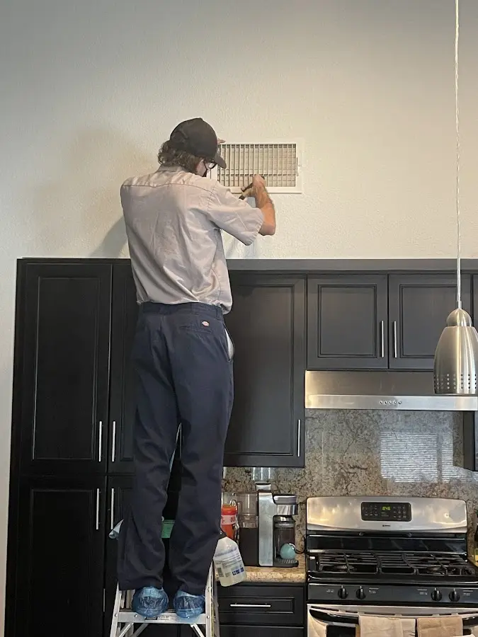 Technician inspecting an air vent during HVAC service in Celina